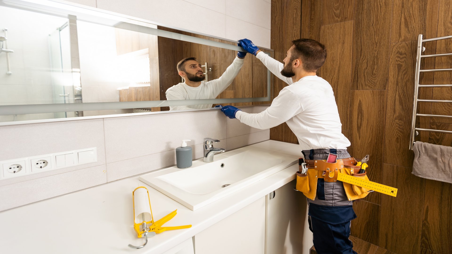 The,Worker,Installs,The,Mirror,In,The,Bathroom.